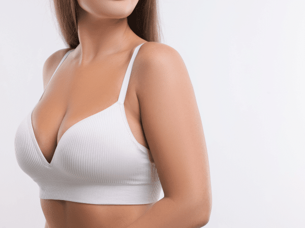 A woman, who have done breast lift procedure, wearing a white bra