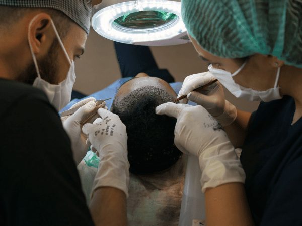 a man getting a hair transplant treatment in Thailand by two Thai expert doctors
