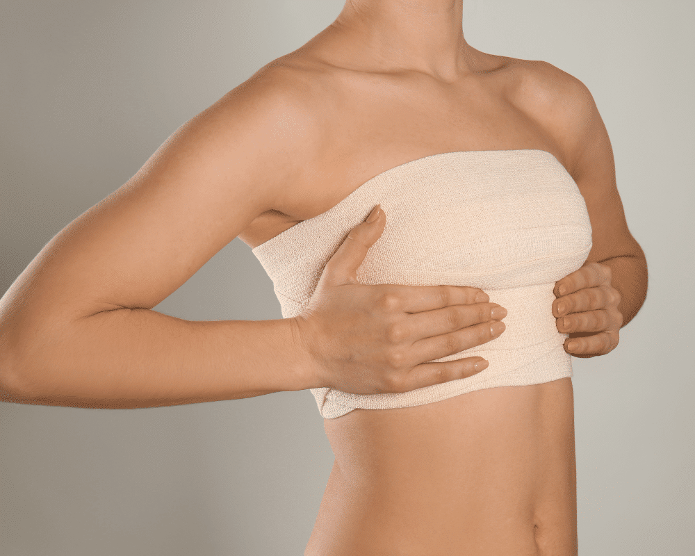 Woman after a breast augmentation surgery wearing a bandage on her chest