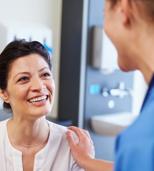 A woman patient sitting in a clinic in front of an expert surgeon that is about to give her an personalised quote